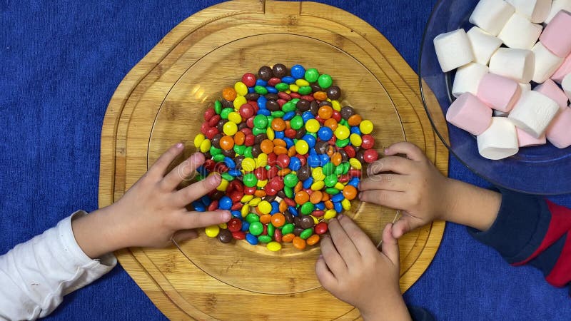 Niños no pacientes jugando con caramelos coloridos colocados en tablero de madera. paro plano