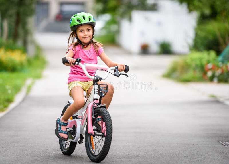 Niños que aprenden conducir una bicicleta en una calzada afuera fotografía de archivo