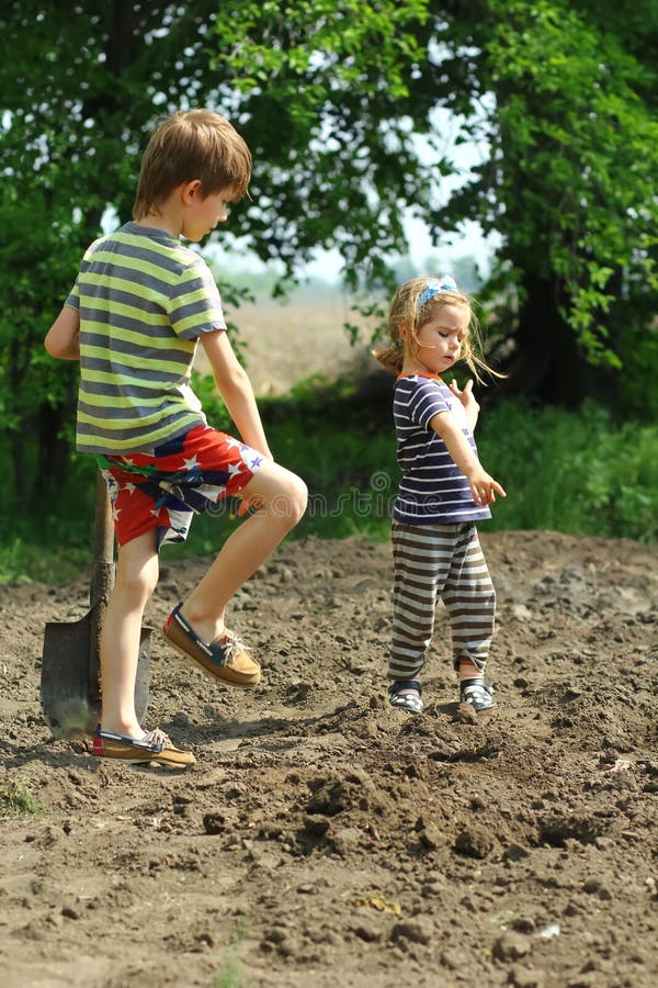 Niños que ayudan a plantar las patatas en el jardín fotografía de archivo Niños que ayudan a plantar las patatas en el jardín fotografía de archivo