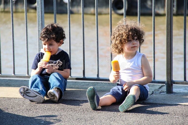 London, UK - June 18, 2016 - Kids eating ice lollies on London's South Bank in summer. London, UK - June 18, 2016 - Kids eating ice lollies on London's South Bank in summer