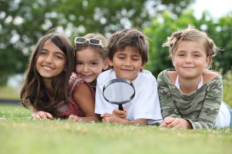 Niños que juegan con la lupa foto de archivo Niños que juegan con la lupa foto de archivo