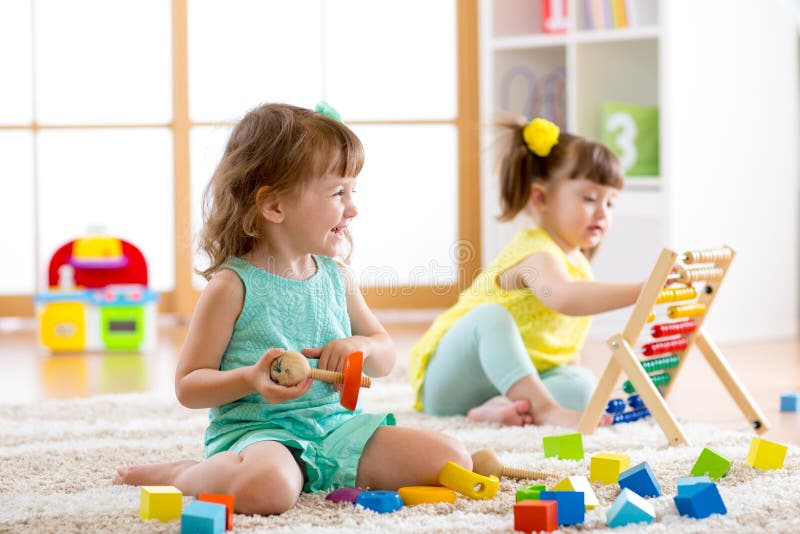 Niños que juegan con los juguetes del ábaco y del constructor en centro de la guardería, del playschool o de guardería imágenes de archivo libres de regalías Niños que juegan con los juguetes del ábaco y del constructor en centro de la guardería, del playschool o de guardería imágenes de archivo libres de regalías
