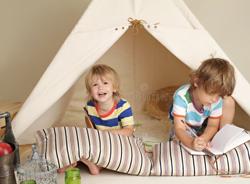 Niños que juegan en casa dentro con una tienda de la tienda de los indios norteamericanos imágenes de archivo libres de regalías Niños que juegan en casa dentro con una tienda de la tienda de los indios norteamericanos imágenes de archivo libres de regalías