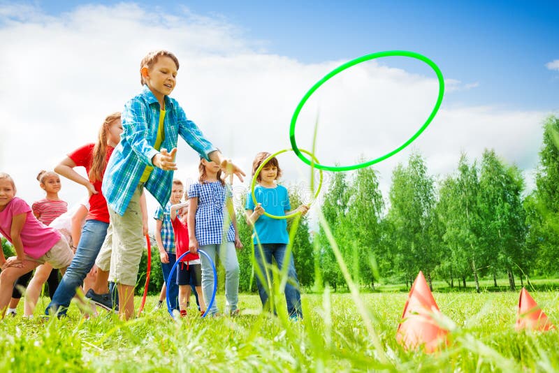 Niños que juegan y que lanzan aros coloridos foto de archivo libre de regalías