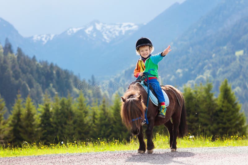 Niños que montan el potro Niño en caballo en montañas de las montañas foto de archivo libre de regalías Niños que montan el potro Niño en caballo en montañas de las montañas foto de archivo libre de regalías