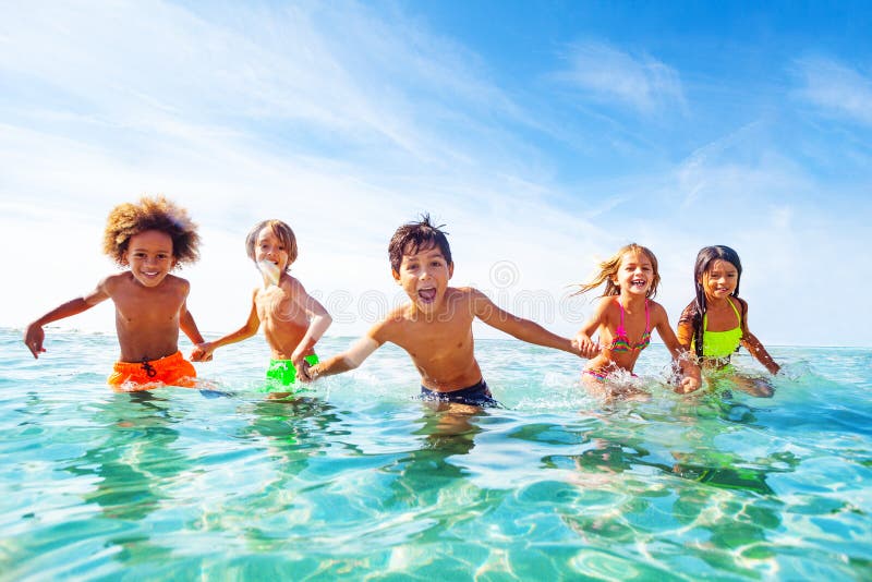 Niños que ríen y que juegan en agua en la playa imagen de archivo libre de regalías Niños que ríen y que juegan en agua en la playa imagen de archivo libre de regalías