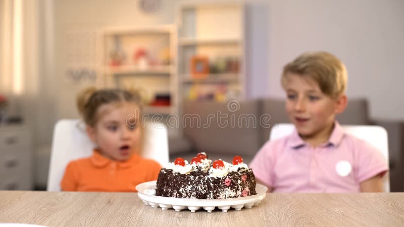 Niños sorprendidos que miran la torta de chocolate, fiesta de cumpleaños, gusto por lo dulce imágenes de archivo libres de regalías Niños sorprendidos que miran la torta de chocolate, fiesta de cumpleaños, gusto por lo dulce imágenes de archivo libres de regalías