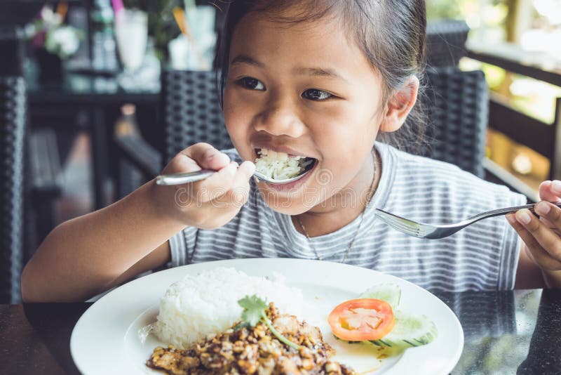 Niños tailandeses que comen en restaurante