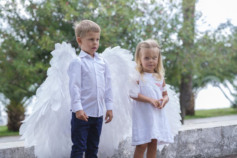 Niños vestidos como ángeles caminan por el parque fotos de archivo