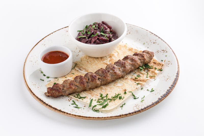 No espeto shish cozinhado do kofte do kofta do cordeiro com feijões e pão árabe isolado no fundo branco fotografia de stock royalty free No espeto shish cozinhado do kofte do kofta do cordeiro com feijões e pão árabe isolado no fundo branco fotografia de stock royalty free