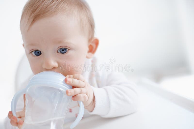 No more bottles for the big boy. Cropped image a cute baby boy drinking from his sippy cup.