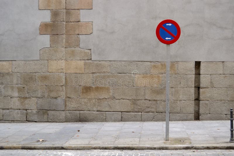 No parking sign, sidewalk and grey wall