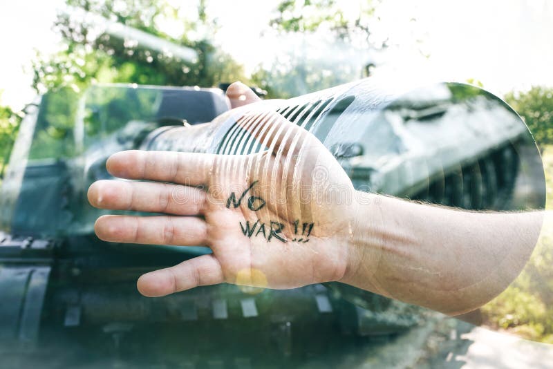 No war sign concept is written on the hand palm. Man is standing near the old tank from the Second World in the green forest. Armored fighting vehicle as a royalty free stock image No war sign concept is written on the hand palm. Man is standing near the old tank from the Second World in the green forest. Armored fighting vehicle as a royalty free stock image