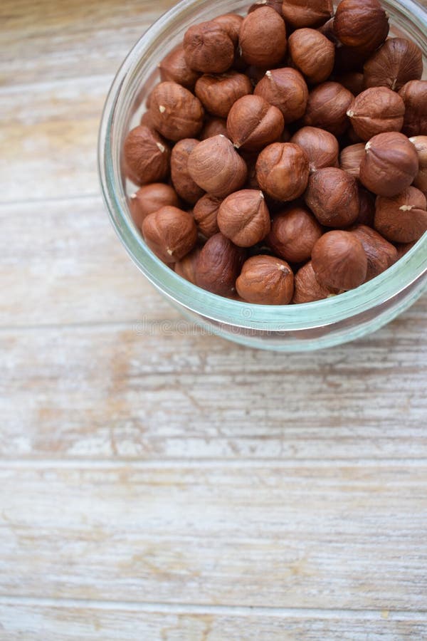 Nocciole in un barattolo di vetro nei precedenti dell'albero Copi lo spazio fotografia stock Nocciole in un barattolo di vetro nei precedenti dell'albero Copi lo spazio fotografia stock