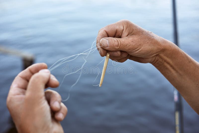 Nod de linie de pescuit masculin netangențial, fără chip, peste apă, pe fond necunoscut, care deține în mână o linie de pescuit cu stock image