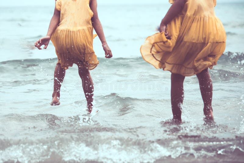 Leg of two asian little child girls jumping and playing on beach together in summer vacation in vintage color tone. Leg of two asian little child girls jumping and playing on beach together in summer vacation in vintage color tone