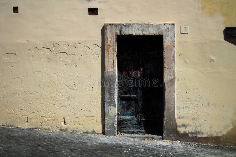 Noircissez la porte brûlée, contrastant avec elle les murs pâles de pêche du ` s et le cadre âgé, à Rome Italie photo libre de droits Noircissez la porte brûlée, contrastant avec elle les murs pâles de pêche du ` s et le cadre âgé, à Rome Italie photo libre de droits