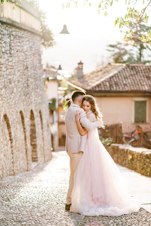 Noiva Abraça Noiva Com Um Belo Vestido Com Um Buquê De Flores No Fundo De  Edifícios Antigos Em Bergamo Itália Foto de Stock - Imagem de buquê, antigo:  217686942