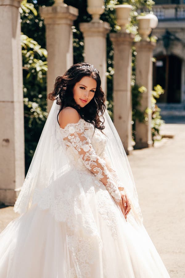 Noiva bonita com cabelo escuro no vestido de casamento luxuoso no ele foto de stock Noiva bonita com cabelo escuro no vestido de casamento luxuoso no ele foto de stock