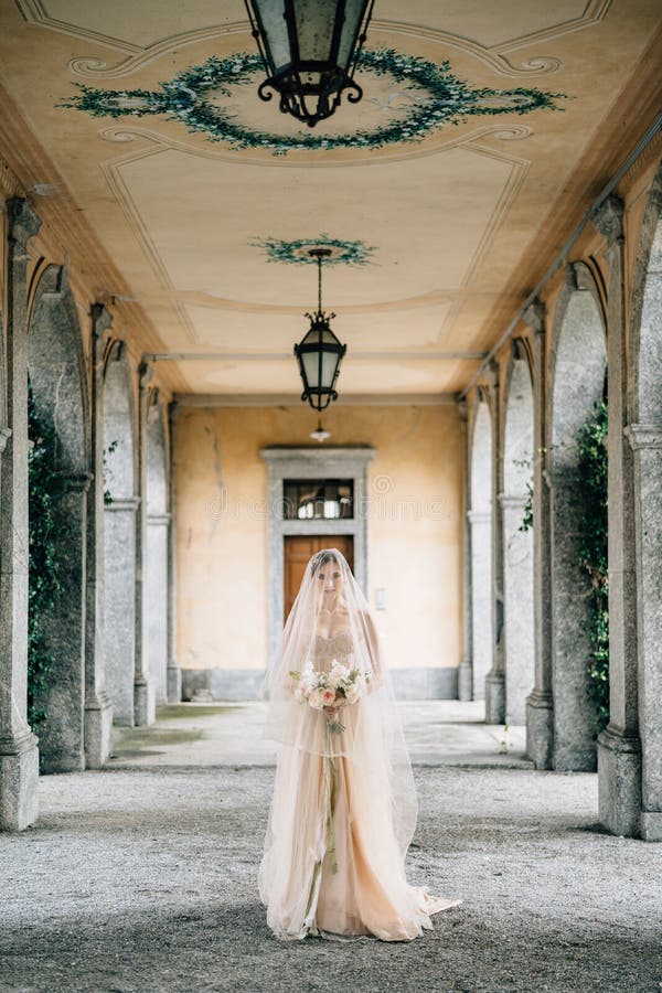 Noiva Com Um Vestido De Noiva E Um Véu Com Um Buquê Caminha Pelo Antigo  Terraço Com Colunas. Lago Como Foto de Stock - Imagem de ternura, casamento:  217945354