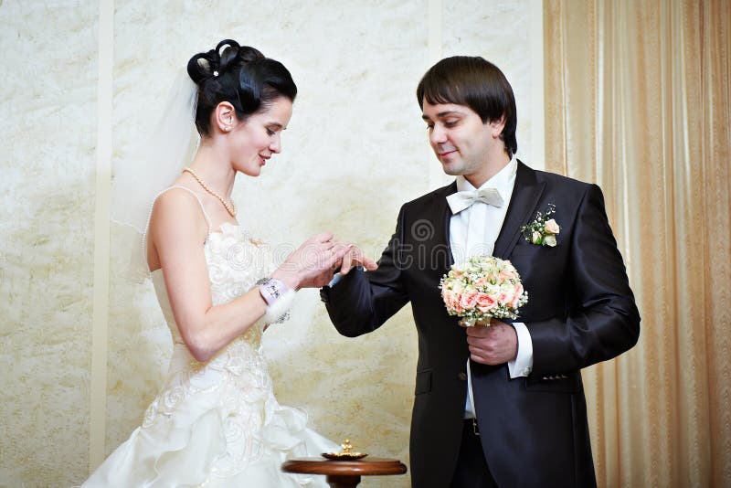 A noiva feliz veste a aliança de casamento seu noivo foto de stock A noiva feliz veste a aliança de casamento seu noivo foto de stock