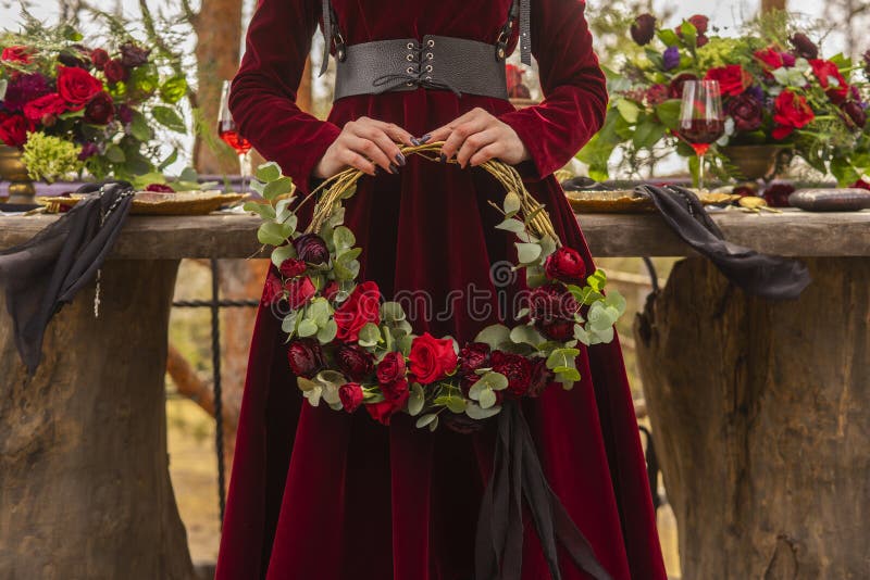 A noiva gótico da menina que veste um vestido vermelho de brocado guarda uma grinalda de imagens de stock A noiva gótico da menina que veste um vestido vermelho de brocado guarda uma grinalda de imagens de stock