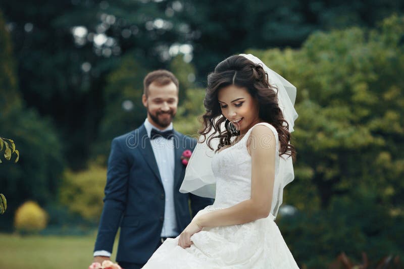 Noiva moreno lindo no vestido elegante que levanta no parque com imagem de stock Noiva moreno lindo no vestido elegante que levanta no parque com imagem de stock