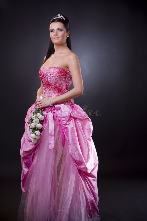 Portrait of a happy young bride posing in a pink wedding dress, holding bouqet of white flowers. Portrait of a happy young bride posing in a pink wedding dress, holding bouqet of white flowers.