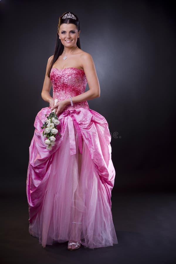 Portrait of a happy young bride posing in a pink wedding dress, holding bouqet of white flowers. Portrait of a happy young bride posing in a pink wedding dress, holding bouqet of white flowers.