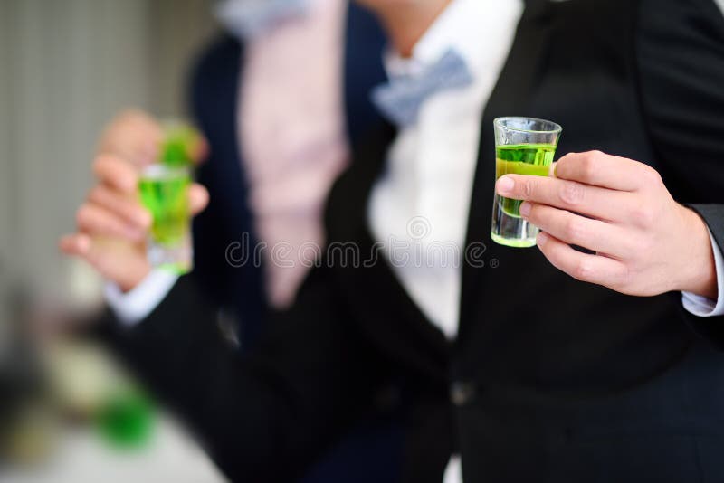 Noivo e o melhor homem que bebem o licor forte do absinto do álcool durante o banquete de casamento imagem de stock Noivo e o melhor homem que bebem o licor forte do absinto do álcool durante o banquete de casamento imagem de stock
