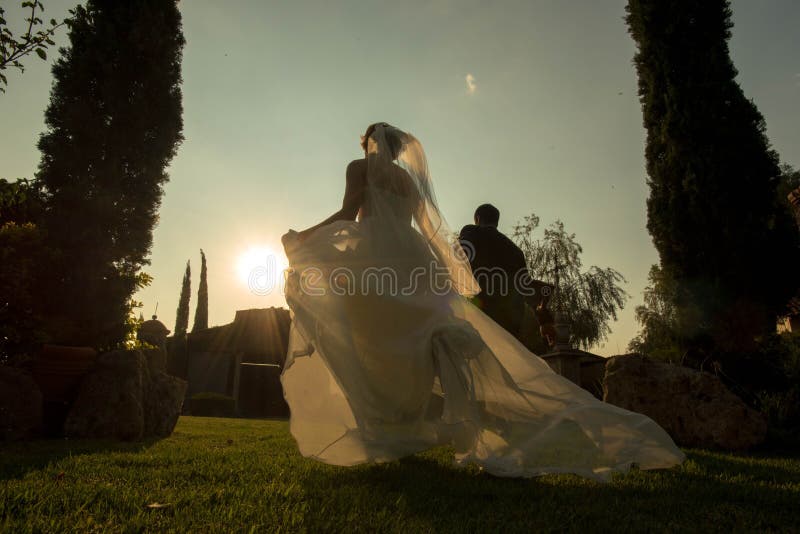 Noivos que correm afastado no por do sol, casamento do jardim no por do sol imagem de stock royalty free Noivos que correm afastado no por do sol, casamento do jardim no por do sol imagem de stock royalty free