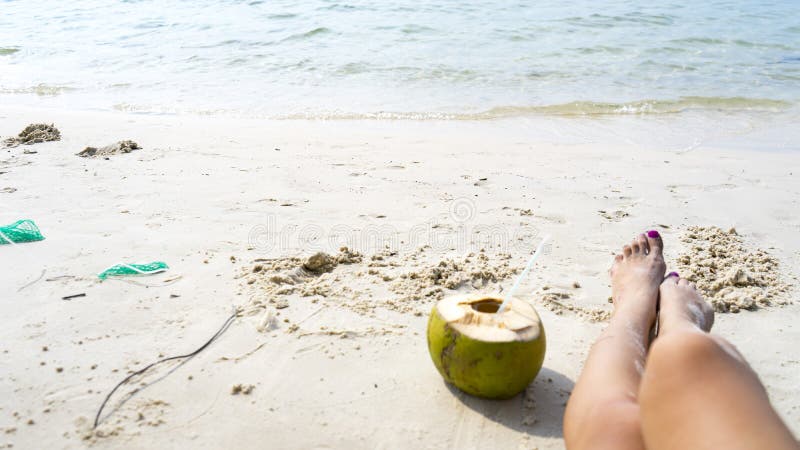 Noix de coco et jambes sur la plage blanche photos libres de droits Noix de coco et jambes sur la plage blanche photos libres de droits