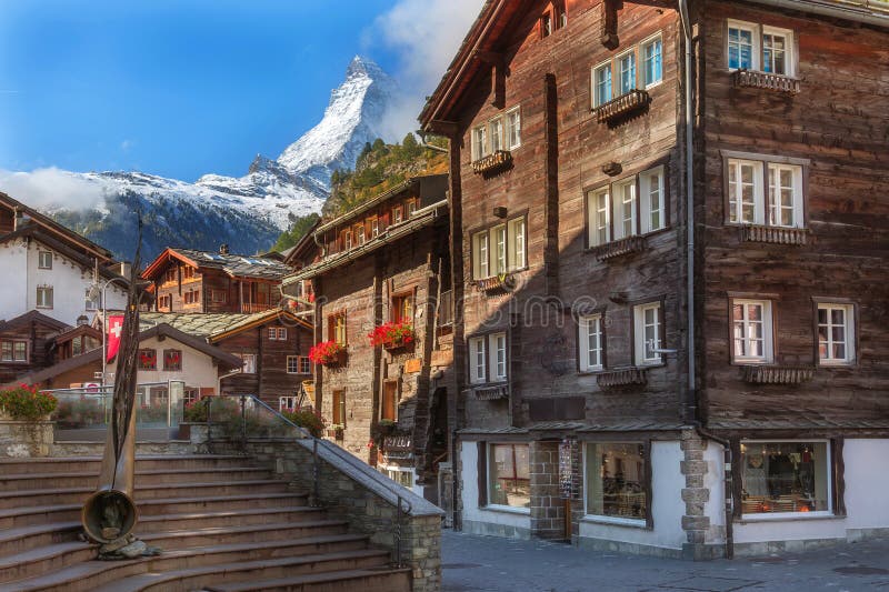 Zermatt, Switzerland iconic town street view in famous Swiss Alps ski resort, Matterhorn snow mount, bronze alphorn and houses. Zermatt, Switzerland iconic town street view in famous Swiss Alps ski resort, Matterhorn snow mount, bronze alphorn and houses