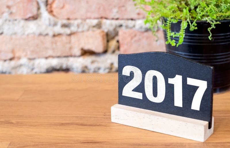 Nombre de la nouvelle année 2017 sur le signe de tableau noir et la plante verte sur le bois image stock Nombre de la nouvelle année 2017 sur le signe de tableau noir et la plante verte sur le bois image stock