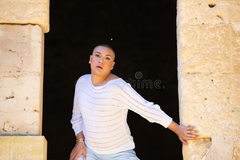 Non binary latin and young person, is in a castle making different body expressions in the hole of the door. Concept of diversity stock photography
