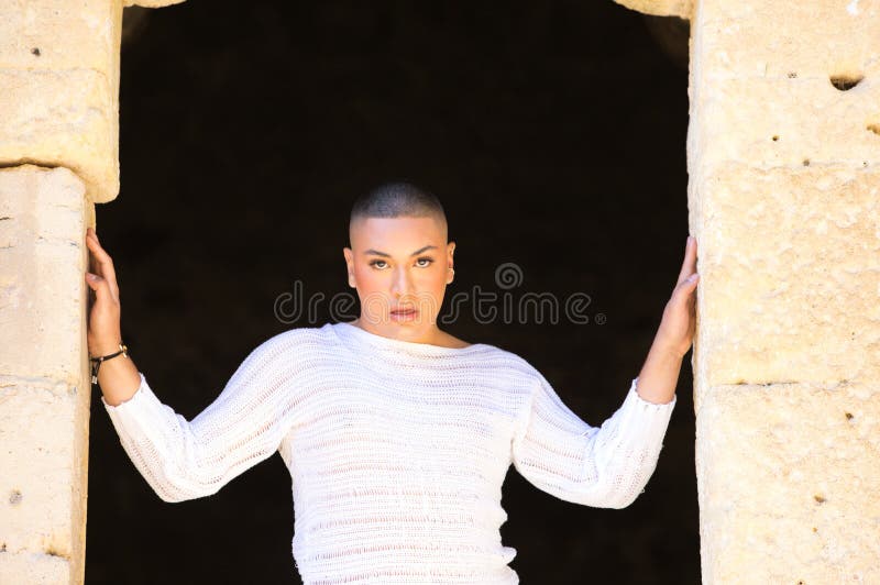 Non binary latin and young person, is in a castle making different body expressions in the hole of the door. Concept of diversity stock image