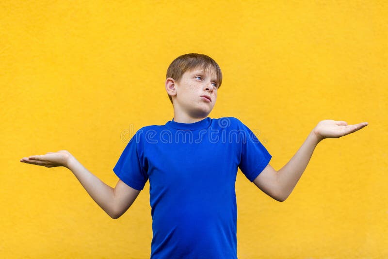 I dont know. Confused young freckled boy. Studio shot, isolated on yellow background. I dont know. Confused young freckled boy. Studio shot, isolated on yellow background