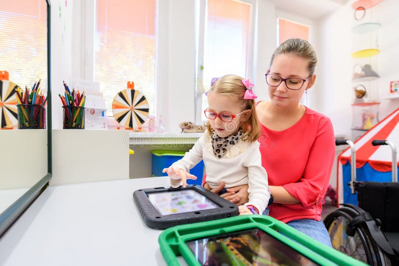 Non-verbal girl living with cerebral palsy, learning to use digital tablet device to communicate.