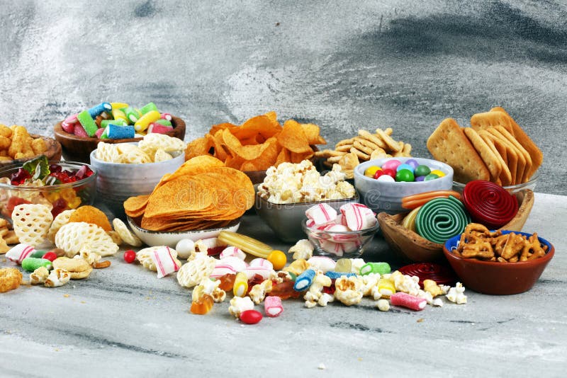 咸味零食。桌上的椒盐卷饼、薯片、饼干和糖果 库存图片