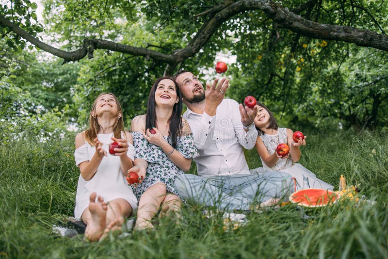 χαρούμενοι γονείς με παιδιά να τρώνε κόκκινα μήλα στο πικνίκ στοκ εικόνα
