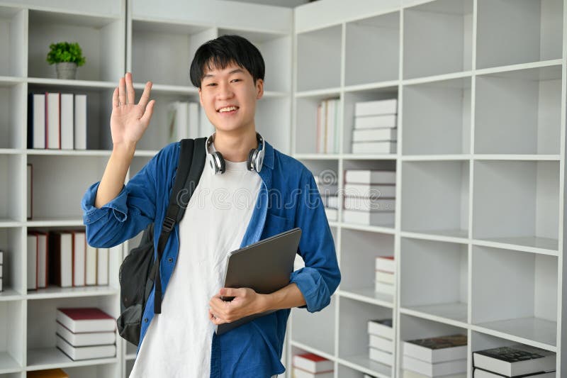 快乐的大学生在书房里向朋友挥手 库存图片