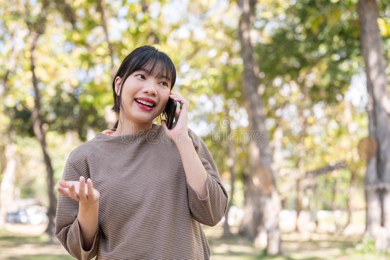 一位女性在公园里散步时，喜欢与朋友在电话里聊天 免版税库存图片