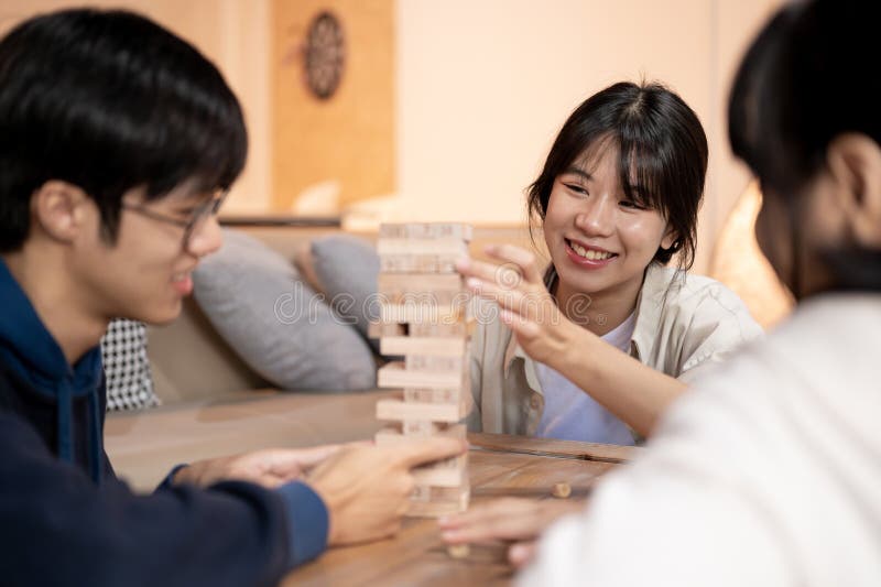 年轻的快乐亚洲朋友喜欢在家玩偶或木块 免版税库存照片