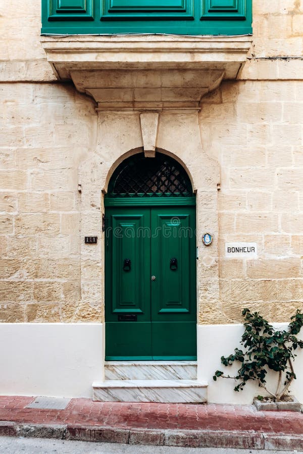 Μια ζωντανή πράσινη διπλή πόρτα με χτυπήματα κεφαλής λιονταριού σε κίτρινο ασβεστόλιθο τοίχου στοκ εικόνες με δικαίωμα ελεύθερης χρήσης