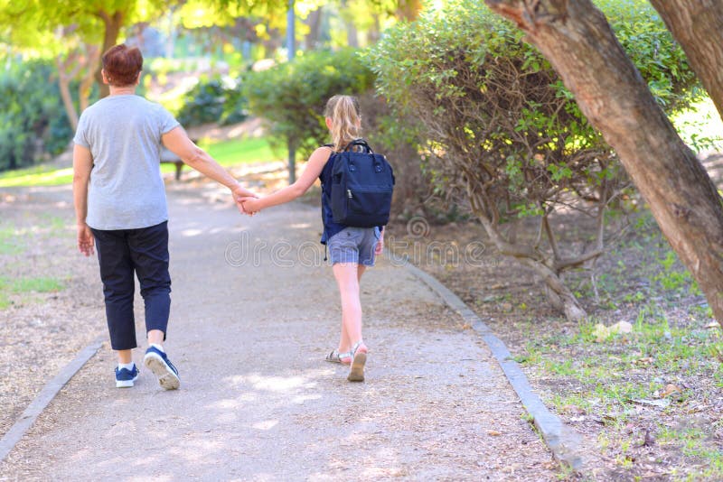 Nonna felice e nipote che camminano alla scuola sulla via nel parco di autunno immagine stock Nonna felice e nipote che camminano alla scuola sulla via nel parco di autunno immagine stock
