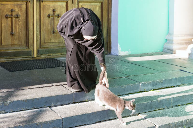 Nonne, die eine Katze streichelt lizenzfreie stockfotografie Nonne, die eine Katze streichelt lizenzfreie stockfotografie