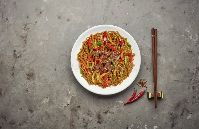 Noodles with beef and vegetables on grey stone background .Top view, copy space