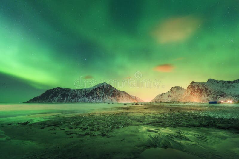 Northern lights in Lofoten islands, Norway. Green Aurora borealis. Starry sky with polar lights. Night winter landscape with aurora, sea with sky reflection, rocks, beach and snowy mountains. Travel. Northern lights in Lofoten islands, Norway. Green Aurora borealis. Starry sky with polar lights. Night winter landscape with aurora, sea with sky reflection, rocks, beach and snowy mountains. Travel