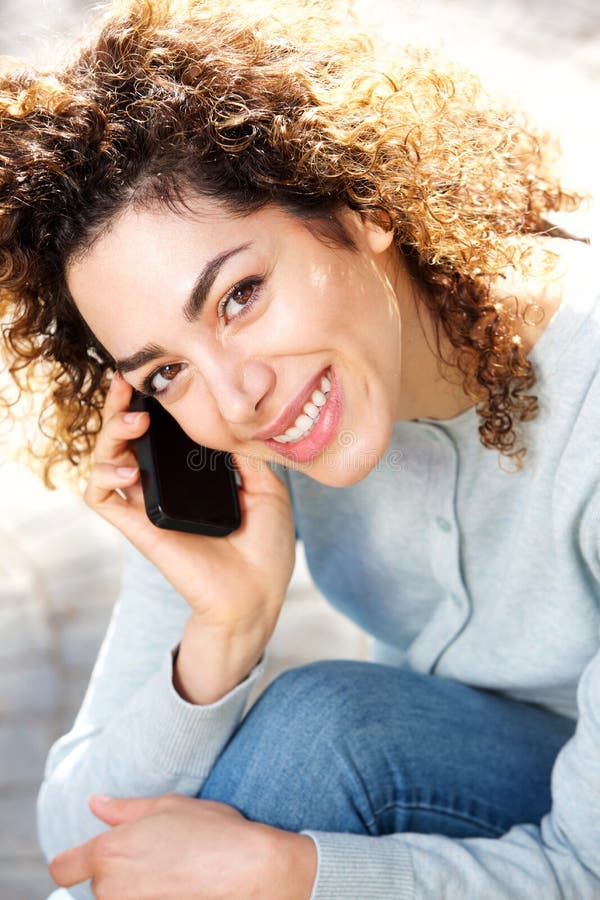 Norr afrikansk kvinna som ler och talar på mobiltelefonen royaltyfri bild Norr afrikansk kvinna som ler och talar på mobiltelefonen royaltyfri bild