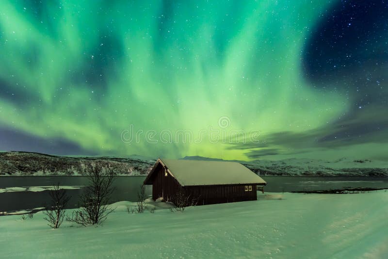 Northern lights Aurora Borealis in the night above a typically a. Rtic style build house in Troms county, Norway. The sky is a bit clouded the landscape is lit royalty free stock images Northern lights Aurora Borealis in the night above a typically a. Rtic style build house in Troms county, Norway. The sky is a bit clouded the landscape is lit royalty free stock images